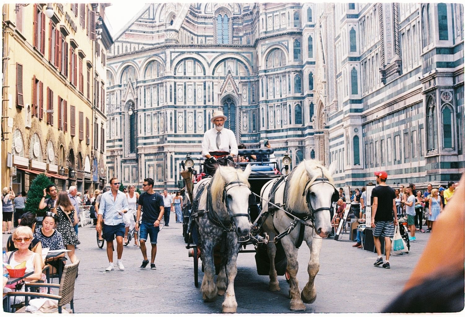 A man riding horse carriage in the middle of Florence, Italy