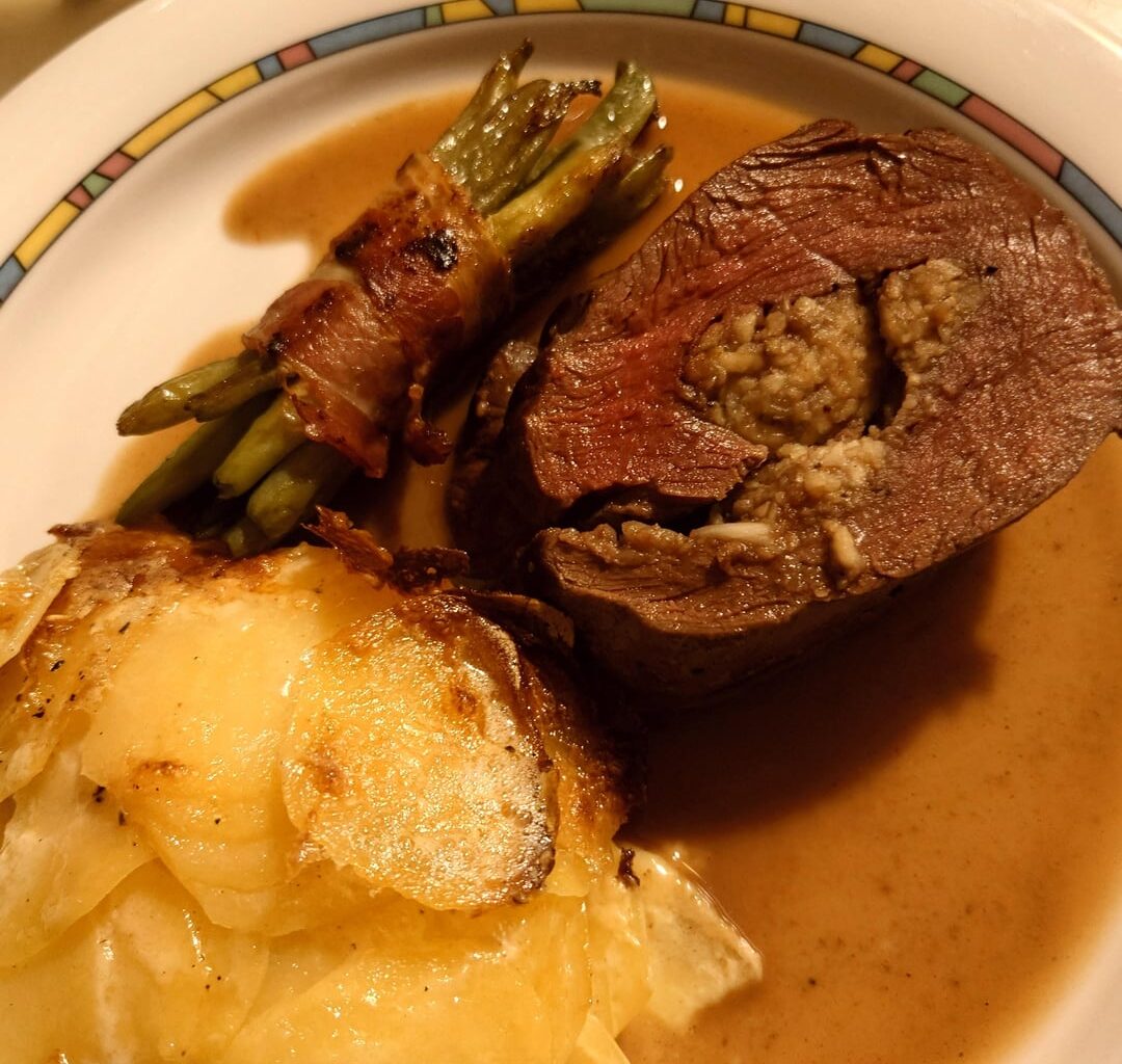 Hirschrollbraten mit Maronenfüllung, Bohnen im Speckmantel und Kartoffelgratin mit Portwein Jus und Panna Cotta mit Himbeersauce