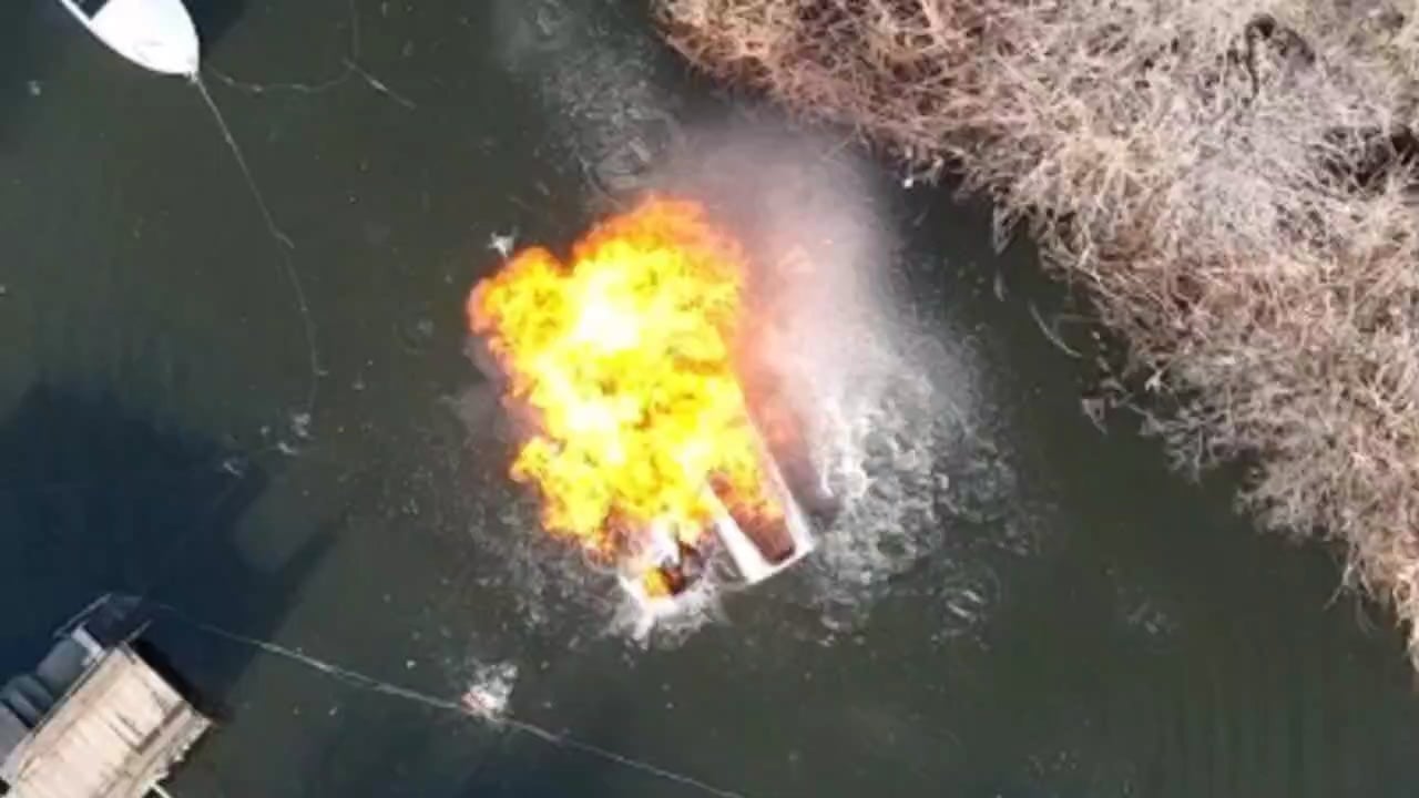 Two Russian soldiers on a boat in civilian clothing are hit with an accurate drone dropped grenade strike injuring them and igniting the fuel, they manage to swim to shore but can be seen bleeding heavily.