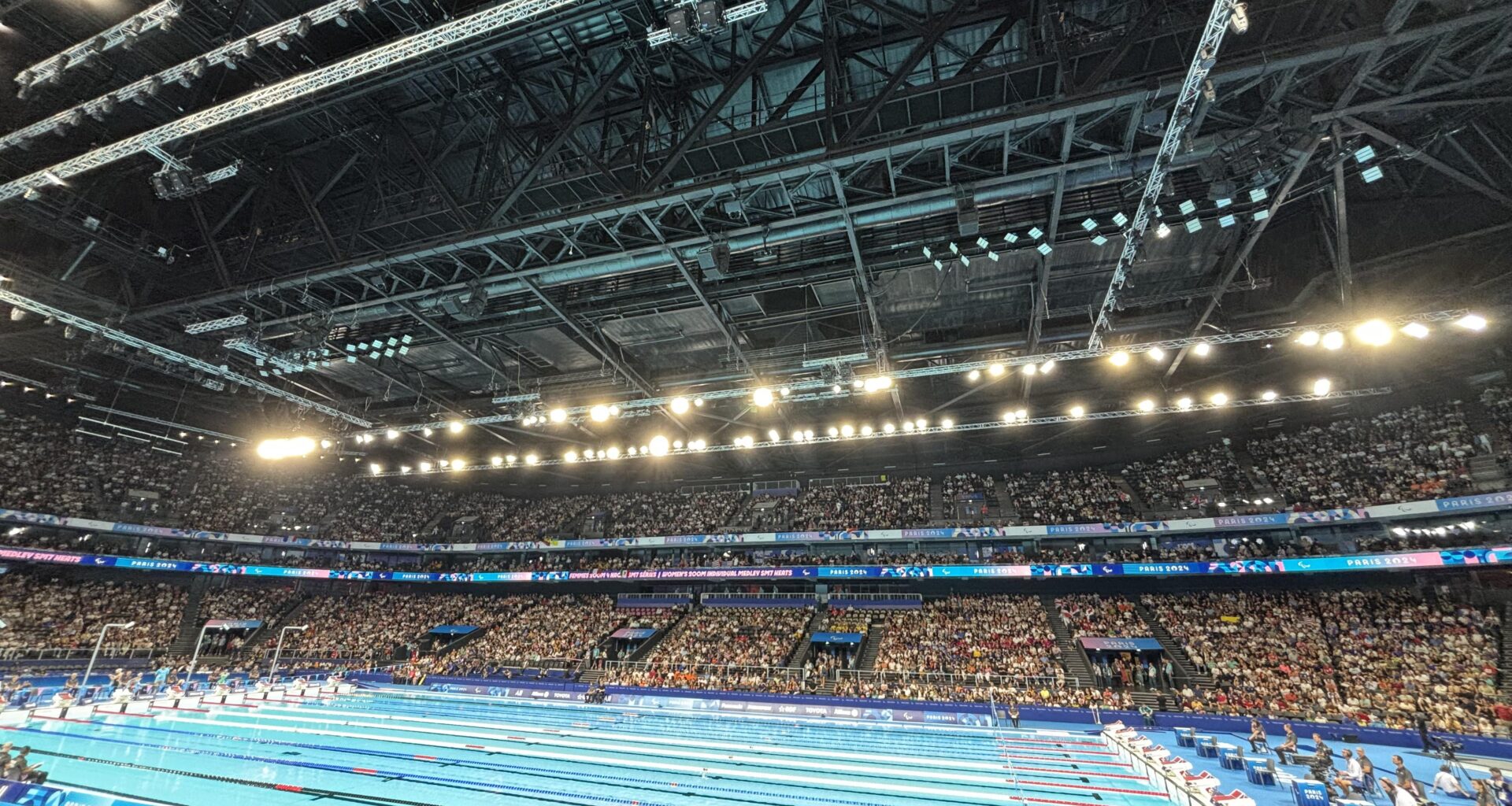 .5 photo from the pool this morning (seated athlete spectator section). I’ve never been to a swim meet like this, the crowd is amazing, especially when a French swimmer races!