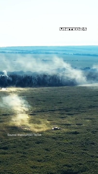 An ostensibly Ukrainian tank fires on a treeline with visible shockwaves from the shells