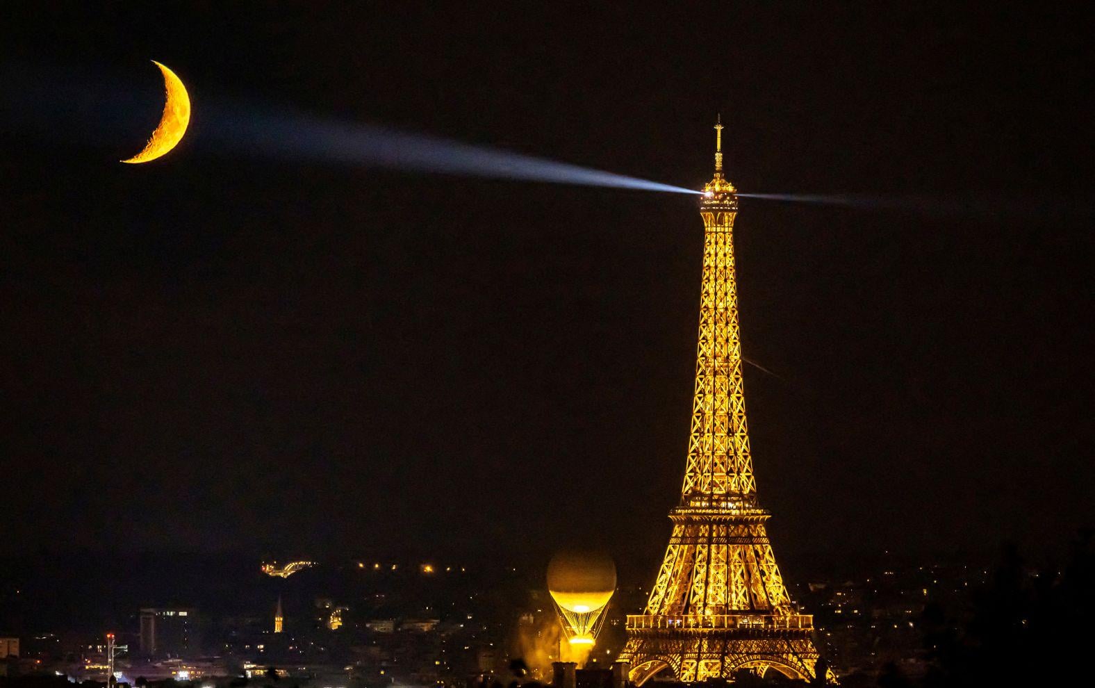 Eiffel and the Moon swap shines as the Olympic flame joins the glow fest. (A photo by Christian Hartmann for Reuters, taken on August 9)