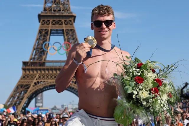 Léon Marchand poses with one of his four gold medals at the Champions Park at Trocadero.