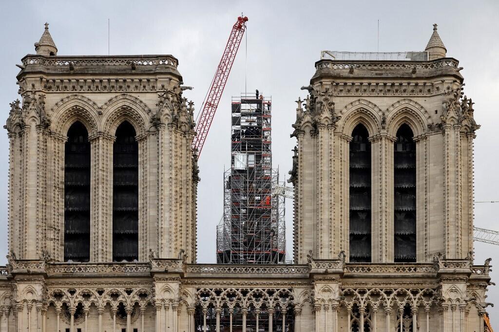 Workers place the cross atop the newly rebuilt spire, as they stand on scaffolding, during reconstruction work, at Notre-Dame de Paris Cathedral, on 6 December 2023.