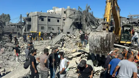 BBC Rescue workers and civilians search for survivors after an Israeli air strike destroyed several buildings near Rafik Hariri University Hospital in southern Beirut, Lebanon (22 October 2024)