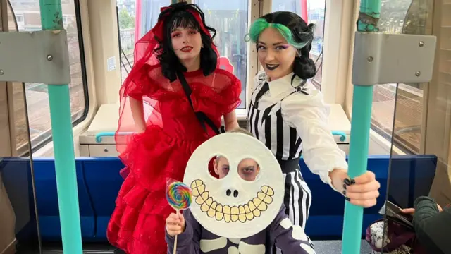 Catherine, Melissa and Tom in Beetlejuice-inspired costume, posing aboard a train