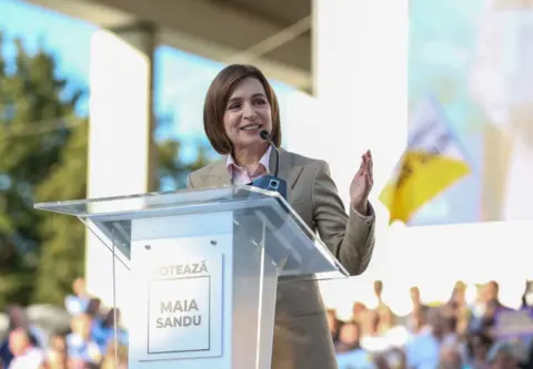 Getty Images Maia Sandu stands at a lectern, delivering a speech