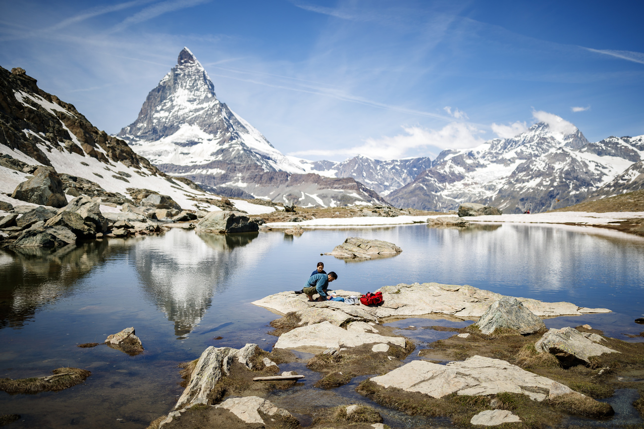 Picture of some tourist near a mountain lake with mountains in the background