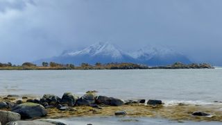 a beach scene with snowcapped mountains on the distant horizon.