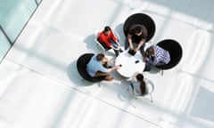 Overhead view of five people sat round a table in discussion