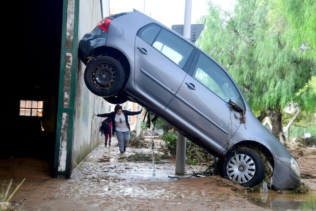 Un residente camina junto a un automóvil levantado en una calle cubierta de barro en una zona inundada en Picanya, cerca de Valencia, este de España, el 30 de octubre de 2024. (Foto de José Jordán / AFP).