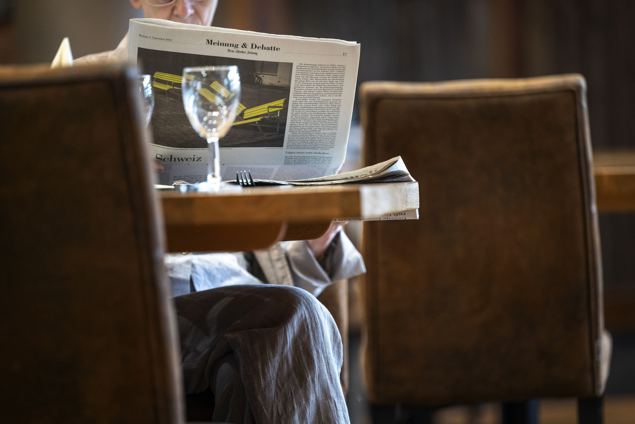 Man reading a newspaper at cafe table in Switzerland