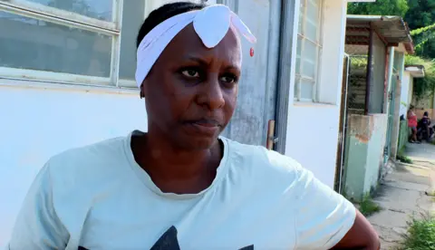 BBC Yusely, a woman wearing a T-shirt and white headband, looks into the camera