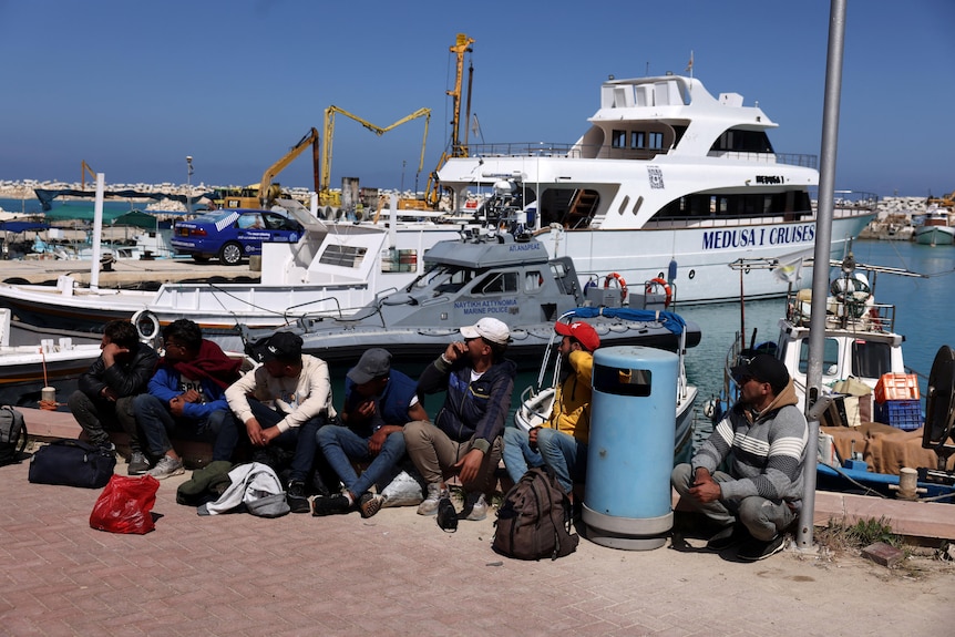 pic of people SITTING NEXT to boat in water