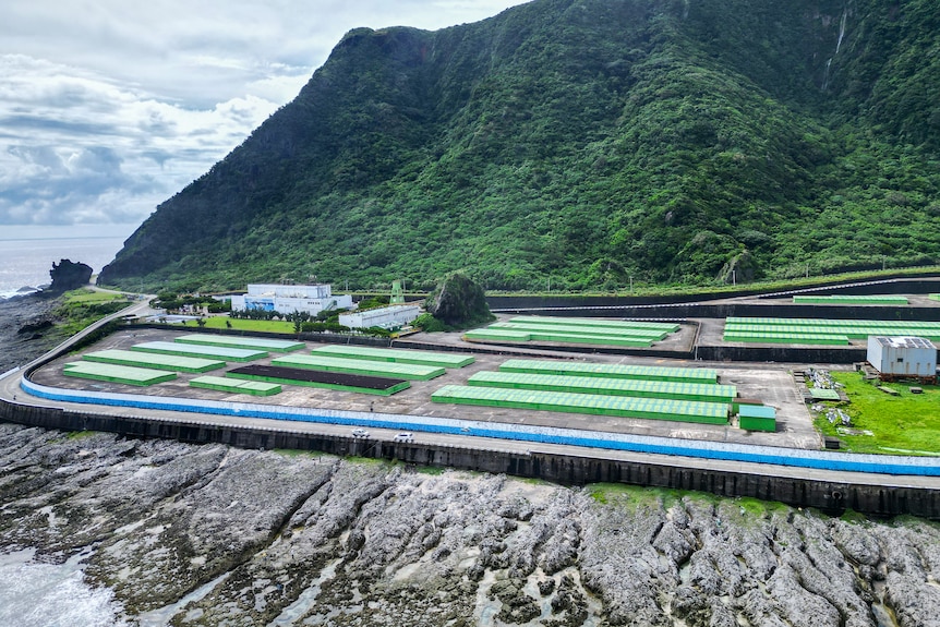 Aerial photo of a large area on the edge of an island covered in large green containers