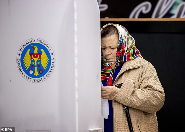 A woman examines her ballot paper in a polling station in Hrusevo village, Moldova, 20 October 2024