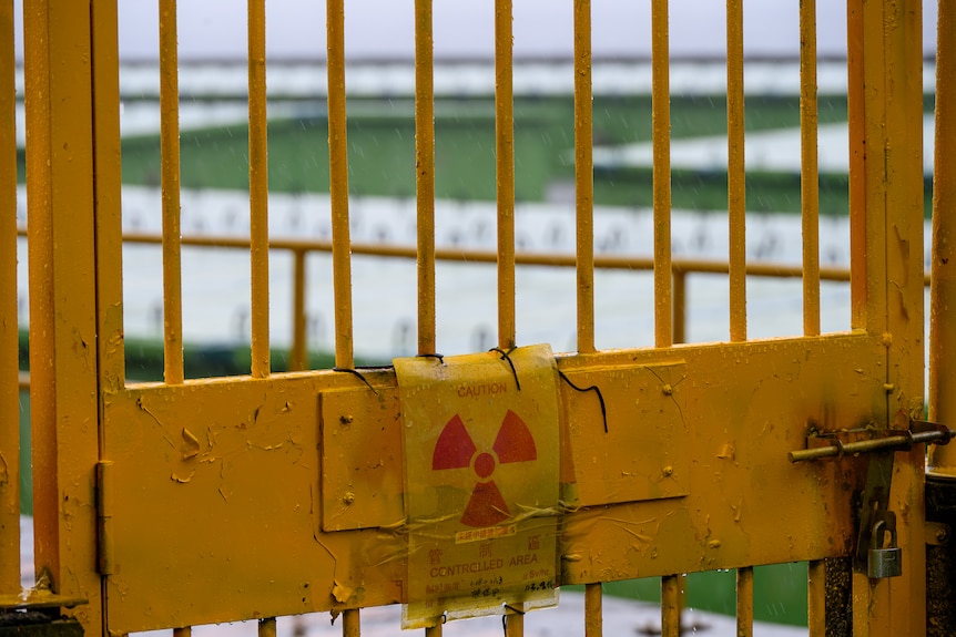 A yellow metal bar gate with the nuclear symbol on it