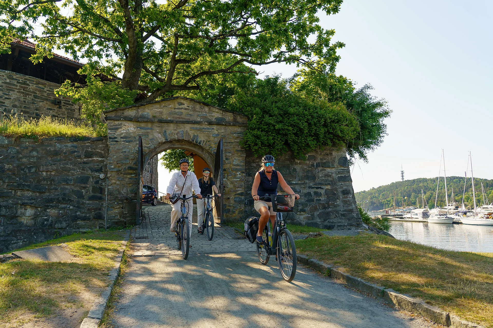 Three people on bikes outside the Christiansholm Fortress in Kristiansand, Norway