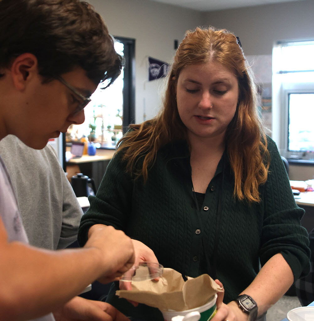 Science teacher Caroline Gambill helps students set up relaxing chambers for the dead bugs.