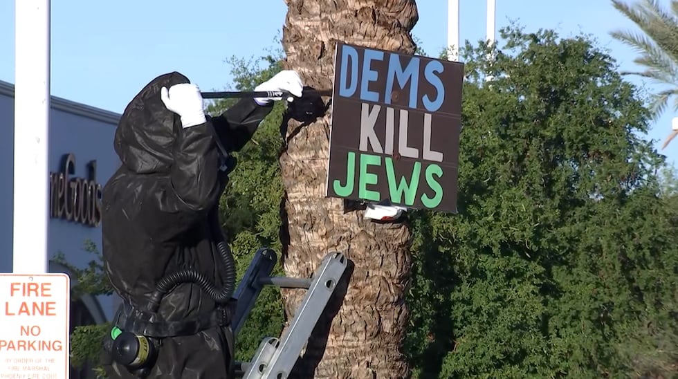 Hazmat teams remove a sign with political messaging an attached bag of white powder from a...