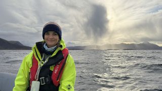 a woman wearing a high visibility all in one smiles at the camera