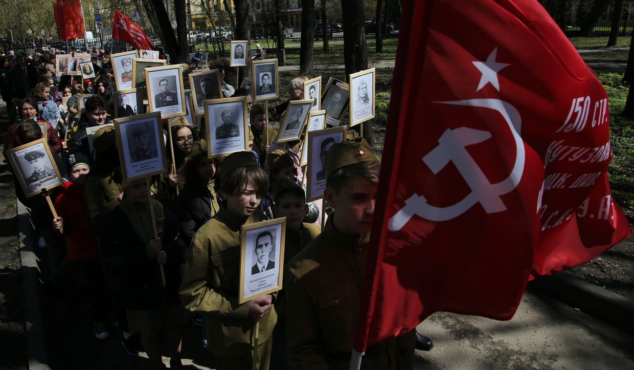 Children carry Soviet flags and portraits of their relatives who participated in World War II during the rally of the Immortal Regiment in Leningradsky Garden in Moscow, Russia