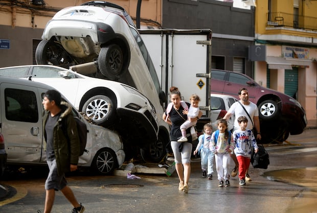 Los residentes caminan junto a automóviles amontonados tras las inundaciones en el barrio de De La Torre de Valencia, al este de España, el 30 de octubre de 2024. (Foto de Rubén FENOLLOSA / AFP).