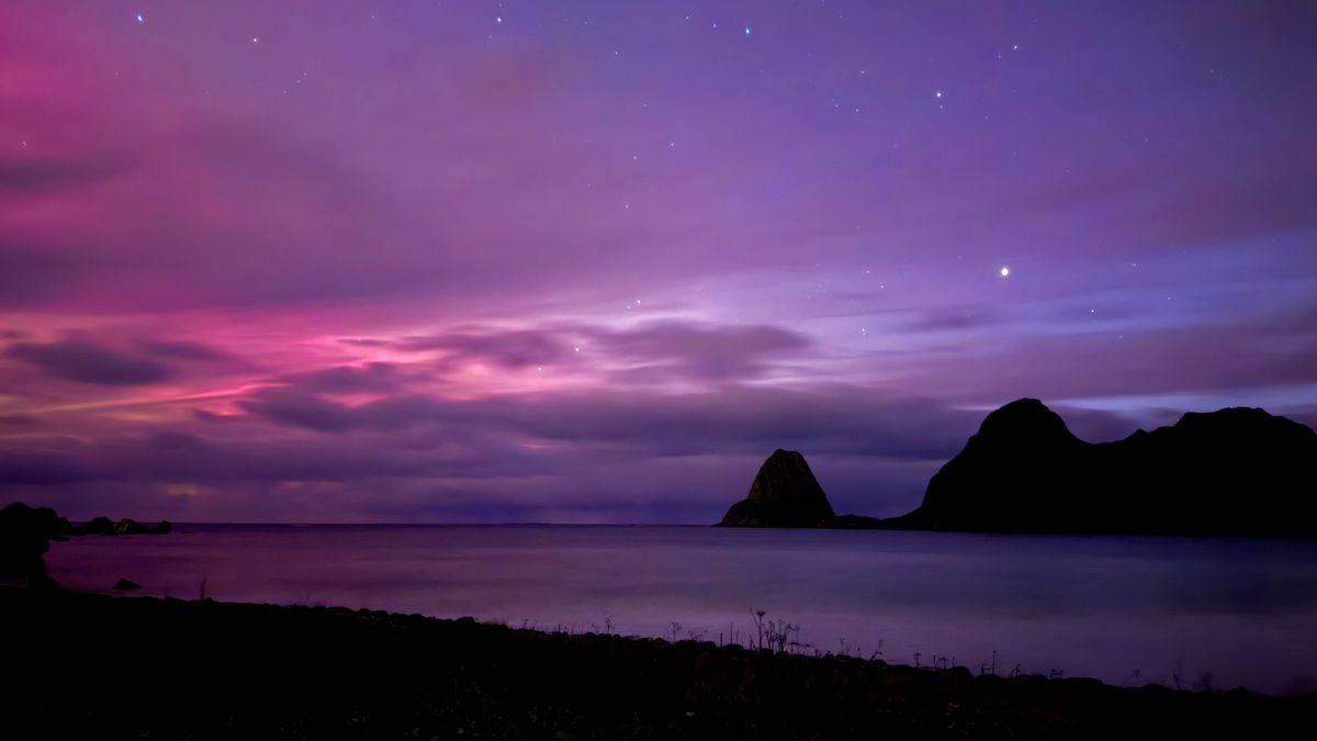 a pink and purple sky with hints of red and faint green on the left. The northern lights make the scene look like a dreamscape.