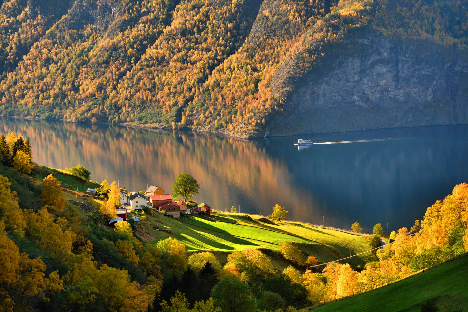 A boat on the water, surrounded by tree-covered mountains.