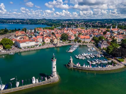 Im Hafen von Lindau befindet sich neben einer Statue des bayerischen Löwen auch ein steinerner Leuchtturm mit Blick auf den Bodensee und die Berge.