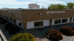 A one story brick building with the company's name is surrounded by decorative gravel and shrubbery.