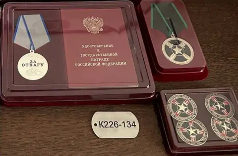 Sergey Vologin family archive/ @jungerbahmut telegram A dog tag inscribed with "K226-134" and a medal engraved with the words "for bravery" 