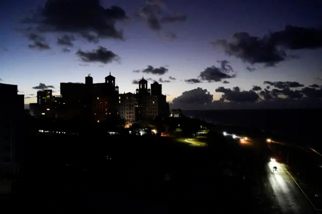 Los automóviles pasan frente al Hotel Nacional y por el malecón de La Habana con todo a oscuras. 