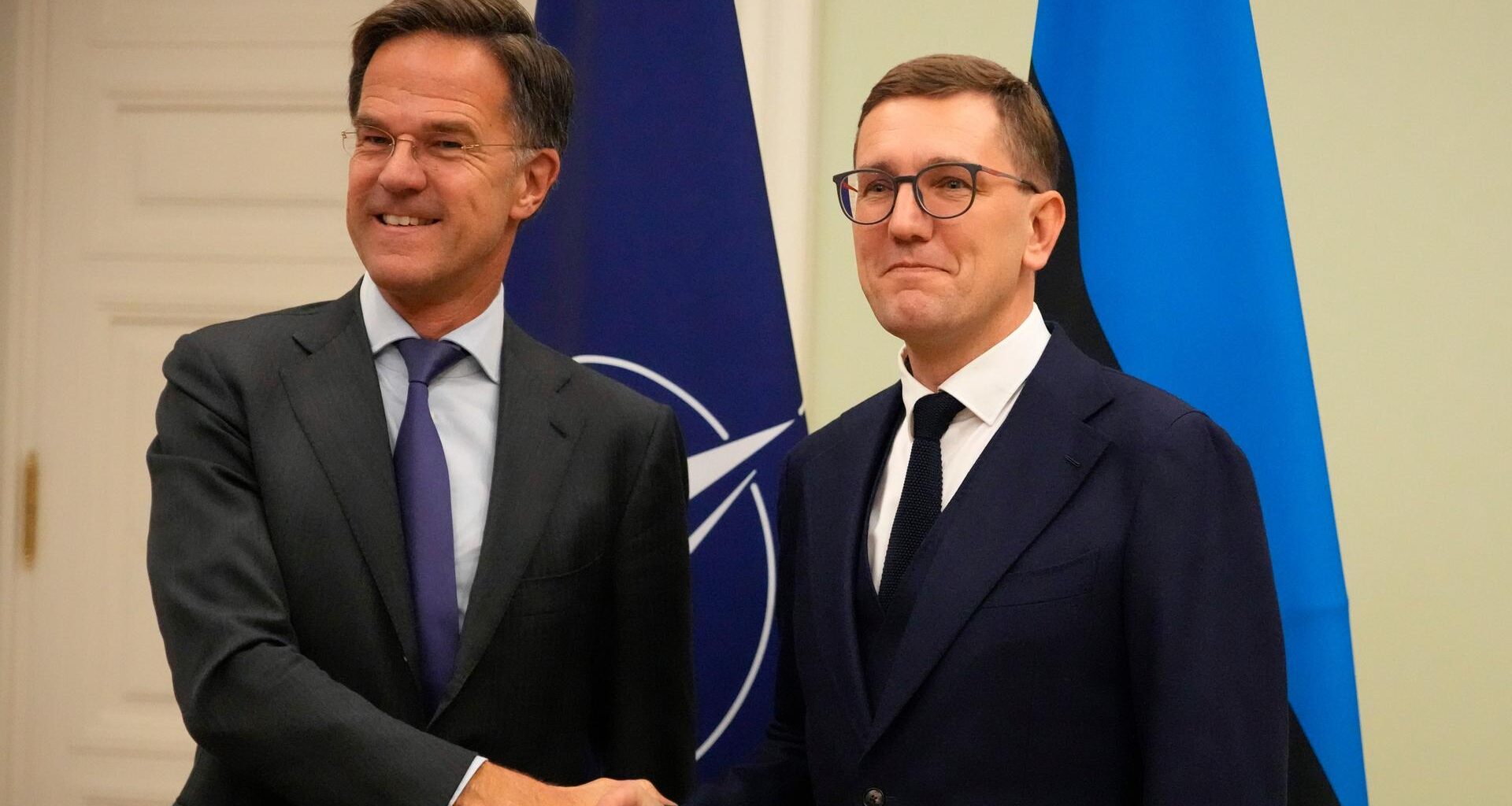 Der estnische Premierminister Kristen Michal und NATO-Generalsekretär Mark Rutte schütteln in Tallinn Hände. Im Hintergrund sind die Flaggen des Verteidigungsbündnisses sowie Estlands zu sehen.