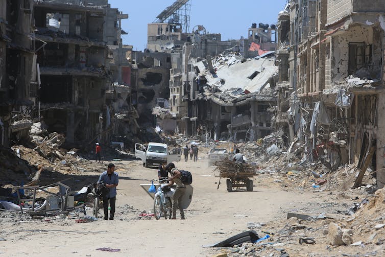 Palestinians walking down a street in Gaza that has been destroyed during the war.