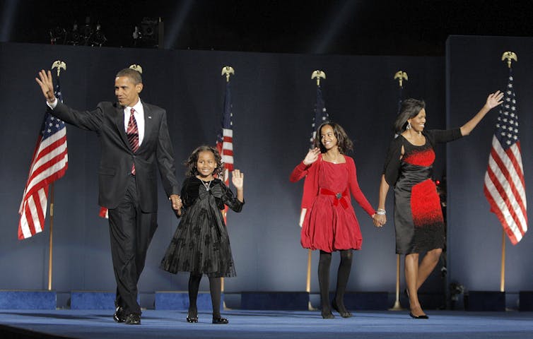 Barack Obama, his wife Michelle Obama, and two daughters, Malia, and Sasha, wave to the crowd at the election night rally in 2008