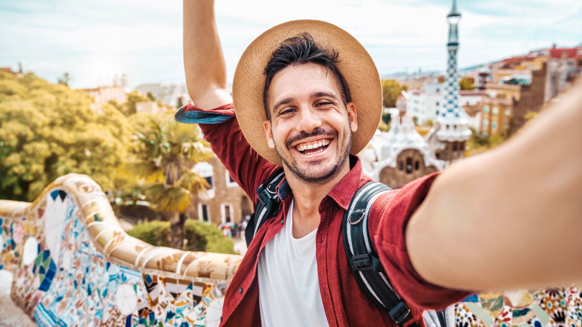 Happy tourist take selfie self-portrait with smartphone in Park Guell, Barcelona, Spain