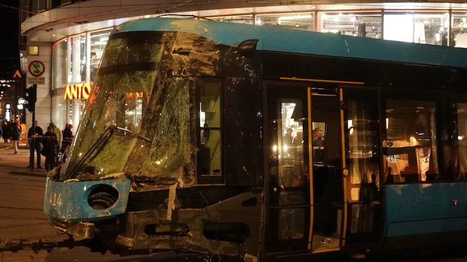 People stand near a tram after it was pulled out of a shop it crashed into, in Oslo, Norway.