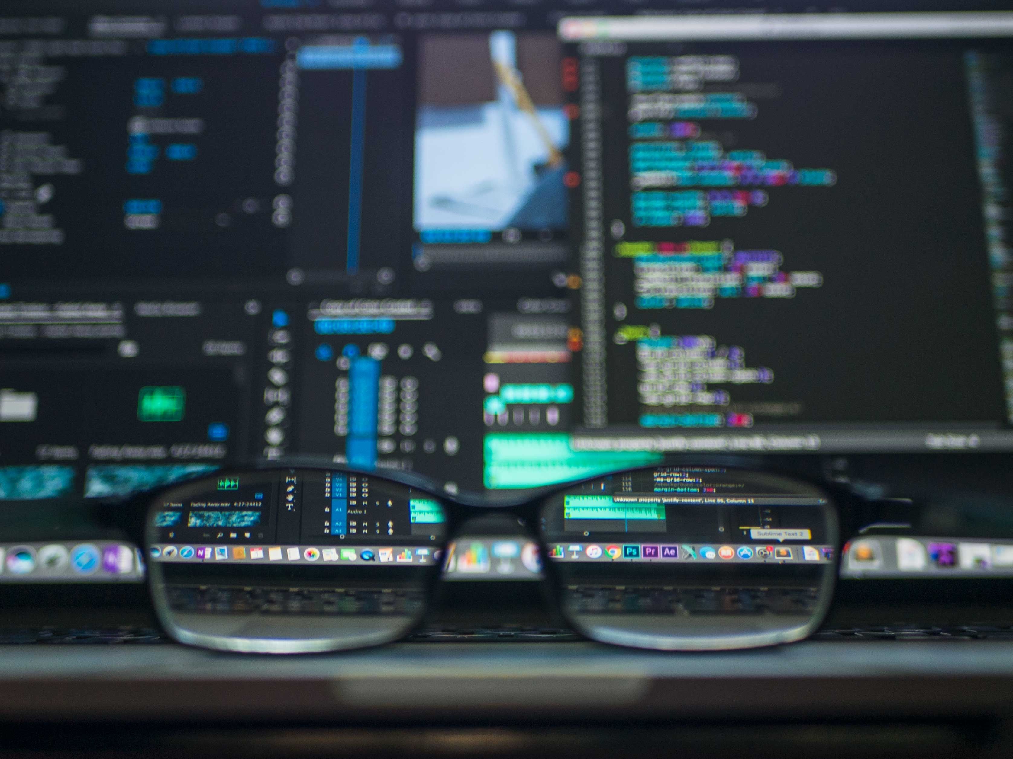 A pair of spectacles balanced on a laptop with the screen showing code