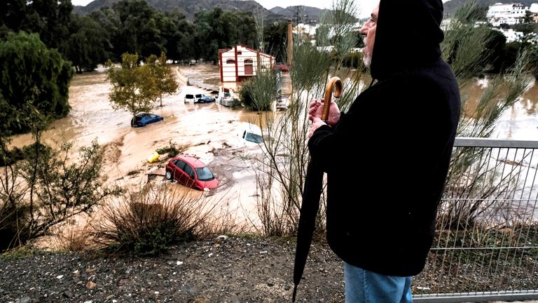 A man observes several cars being swept away by the water, after floods preceded by heavy rains caused the river to overflow its banks in the town of Alora, Malaga, Tuesday, Oct. 29, 2024. (AP Photo/Gregorio Marrero)