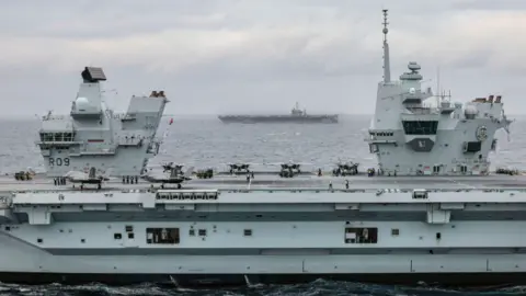 MOD HMS Prince of Wales (foreground) with F-35B Lightning jets on deck, and USS Harry S. Truman (Background)