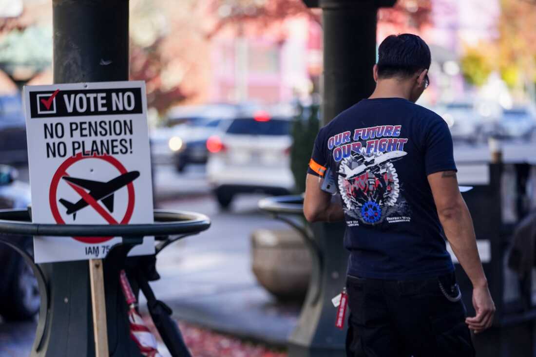 A Boeing employee walks by a picket sign urging people to vote no on a new contract offer from the company on Monday in Everett, Wash.