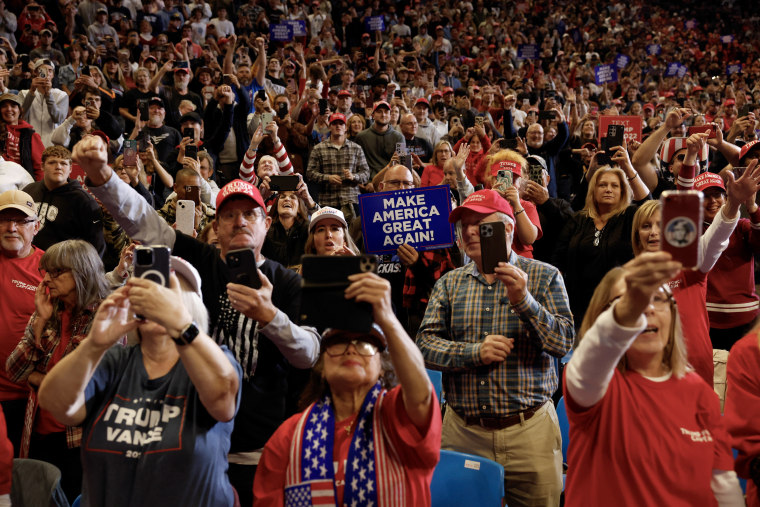 Trump supporters hold signs and phones.