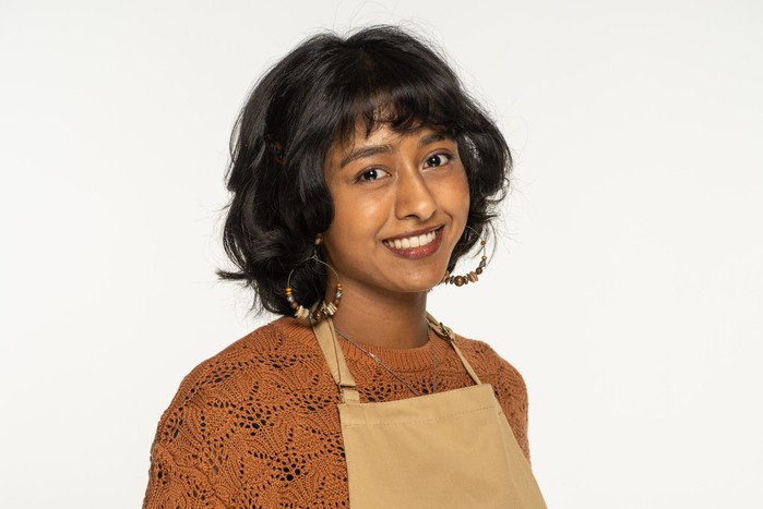 Sumayah wearing an apron in a photo for The Great British Bake Off.