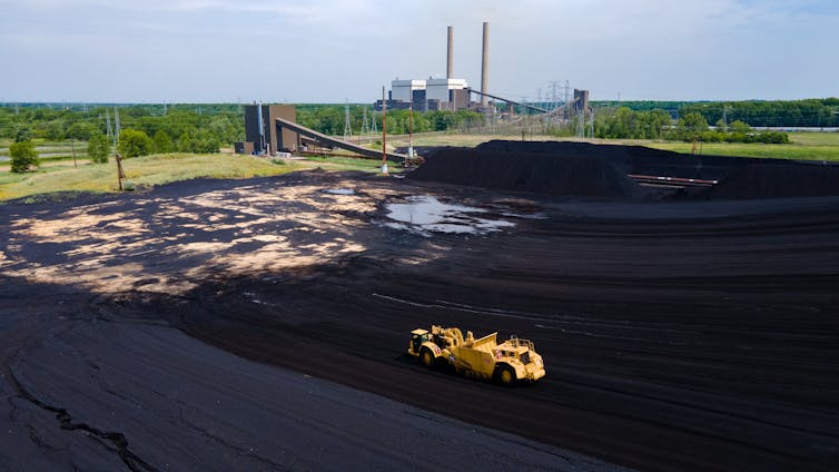 Aerial view of an open-cast coal mine with power plant chimneys in the distance